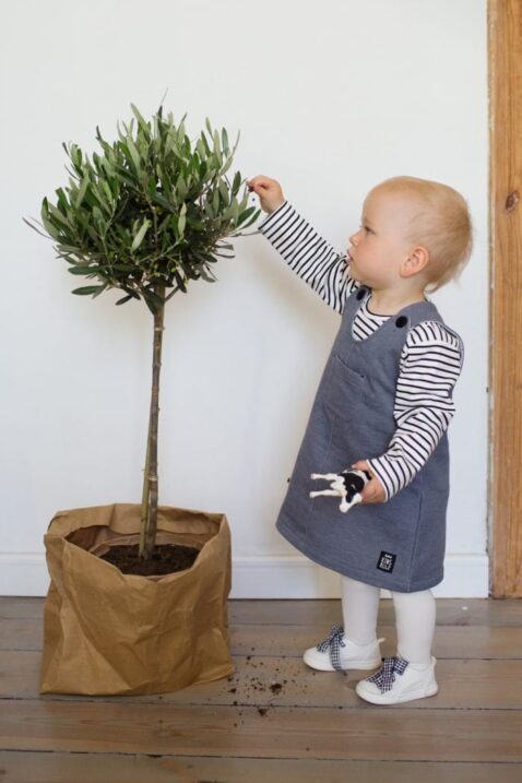 Spielendes Mädchen Baby mit grauem Latzkleid Sweatkleid ärmellos mit Patch, Brusttasche & Knöpfe im strukturierten Design mit schwarz-weiss-gestreiftem Oberteil von Pinokio - Babyphoto