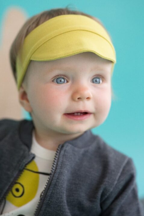 Lachendes Baby mit dunkelgrauer Zip Sweatjacke Pullover strukturiert mit Taschen & Patch, gelber Schildmütze, weißem Hunde Oberteil Body für Jungen & Mädchen von Pinokio - Babyphoto