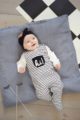 Liegendes lachendes Baby Mädchen mit schwarz-weiß gestreiftem Baby Strampler mit Fuß & Tasche, weißem Oberteil, schwarzem Stirnband - Strampelanzug von Pinokio - Babyphoto