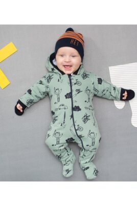 Lachender liegender Junge Baby trägt grünen gefütterten Baby Overall Strampelanzug Einteiler mit Füßen, Kapuze Handschutz, Schulmotiven & orangene schwarz gestreifte Baby Mütze von Pinokio - Babyphoto