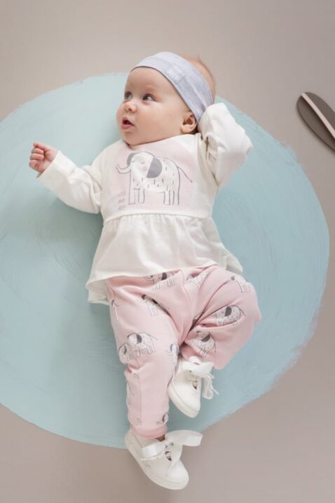 Liegendes Baby Mädchen trägt rosa Sweathose Leggings mit Elefanten - Baby Langarmshirt rosa in Kleidchenoptik Tunika mit Elefant - Graues Stirnband Haarband Basic mit Patch "GO WILD" - Weiße Babyschuhe mit Schleife von Pinokio - Babyphoto