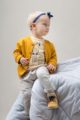 Mädchen trägt Baby Sweatjacke Cardigan mit Knöpfen - Gestreiftes weiß-senfgelbes Langarmshirt mit Papagei - Beige helle Babyhose Pumphose mit Taschen von Pinokio - Babyphoto