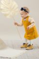 Spielendes Baby Mädchen trägt kurzes Kinder Baumwollkleid Latzkleid in Currygelb - Gestreiftes Shirt Oberteil mit langen Ärmeln & Papagei Motiv von Pinokio - Babyphoto