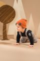 Krabbelnder Junge trägt graue Baby Latzhose Schottenkaro - Schwarzer Body in Polo-Optik mit Bär - Braun orangene Babymütze mit Umschlag von Pinokio - Babyphoto