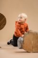 Kniender Junge trägt schwarze Baby Pumphose mit Knöpfe - Braun orange Kapuzenpullover Hoodie mit asymmetrischer Knopfleiste Patch BEAR CLUB von Pinokio - Babyphoto Kinderphoto