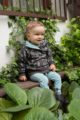 Lächelnder Junge trägt grüne türkise Baby Leggings Babyhose Sweathose mit Satement Patch Umwelt - Braunen Kinder-Hoodie mit Zweige & Blätter Muster von Pinokio - Kinderphoto Babyphoto