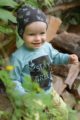 Lächelnder Junge trägt grüne Kinder Baby Pumphose mit Tasche - Braune Mütze mit Blätter & Patch Eule - Türkis grünes Oberteil Langarmshirt STAY GREEN von Pinokio - Babyphoto Kinderphoto