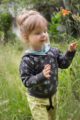 Stehendes Mädchen trägt braunen Kinder Baby Hoodie mit türkis grünen Blätter Muster - Grüne Pumphose Schlupfhose mit Tasche STAY GREEN Print von Pinokio - Babyphoto Kinderphoto