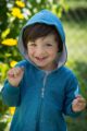 Lachender Junge trägt blauen Kinder Babyoverall mit Kapuze, ohne Fuß, Kängurutasche, Reißverschluss & Auto Patch aus Baumwolle von Pinokio - Babyphoto Kinderphoto