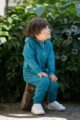 Sitzender Junge trägt türkis blauen Baby Baumwoll Strampler ohne Fuß mit Kapuze, Kängurutasche, Reißverschluss & Retro Auto Car Patch von Pinokio - Babyphoto Kinderphoto