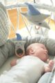 Schlafendes Baby mit blau-grau Holz Beißring Babyrassel & einer Spieluhr mit Melodie Guten Abend Gute Nacht in Sterne-Optik aus zertifizierter OEKO TEX Baumwolle von Nordic Coast Company - Babyphoto