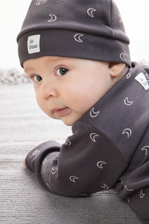 Baby Junge trägt graubraune Zipfelmütze Baumwollmütze mit Halbmonden & Patch BE BRAVE - Kinder Schlafoverall mit Druckknöpfen & Füßen OEKO TEX von Pinokio - Babyphoto Nahaufnahme