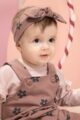 Mädchen trägt dunkelrosa Baby Latzhose Trägerhose mit Blumenmuster - Kinder Stirnband mit Schleife rotbraun - Hellrosa Baby Flower Langarmshirt mit Rüschen & LOVE Print von Pinokio - Kinderfoto Nahaufnahme
