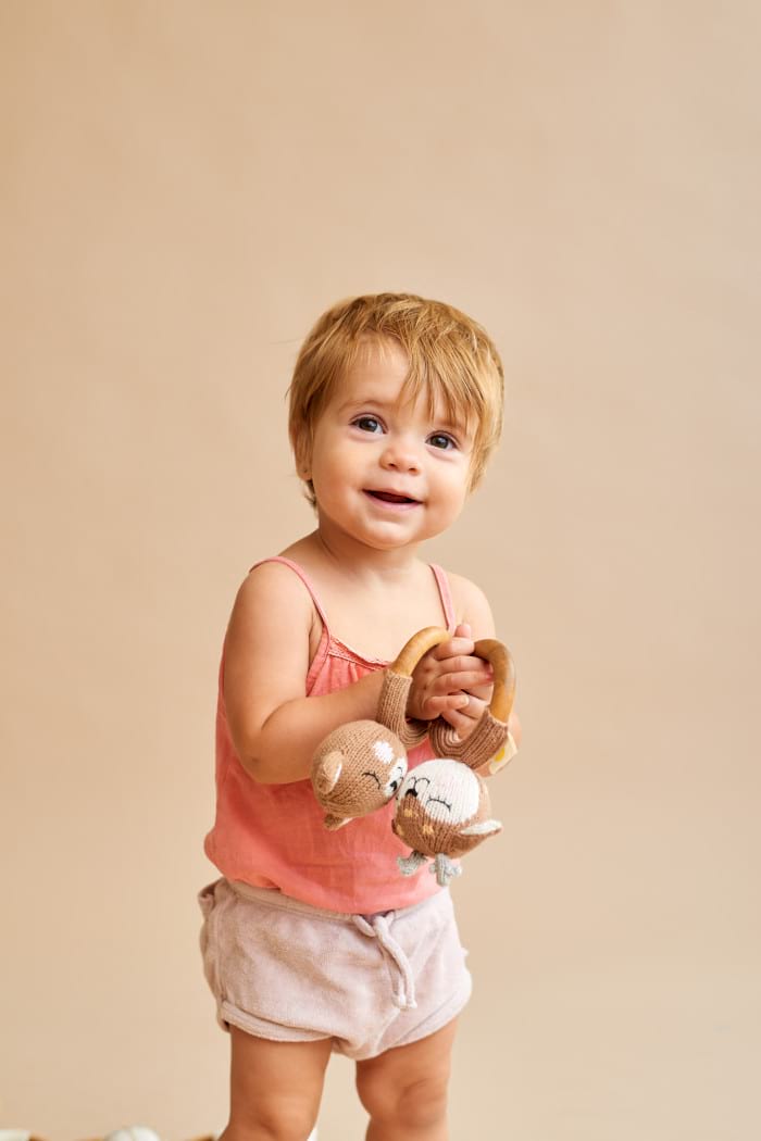 Lachendes Mädchen spielt mit Babyspielzeug Holz Beißring Rassel Strick Bär & Reh aus OEKO TEX Bio Baumwolle handgefertigt Motorikspielzeug von Knit A Buddy - Babyfoto Kinderfoto Set Bär & Rehkitz