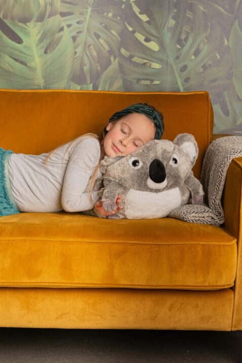 Mädchen schläft auf Kinder 3in1 Koalabär Kuscheltier Muff, Handwärmer, Kopfkissen mit CE Kennzeichnung - Flauschig kuschelig Plüschwärmer mit Eingriffslöcher als Wärmekissen von COZY NOXXIEZ - Kinderfoto