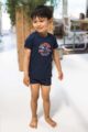 Junge trägt dunkelblaue Baby Kinder Badepants mit Bein und Palmen Muster badehose - T-Shirt mit Print navy von Koko Noko - Kinderfoto Junge am Strand
