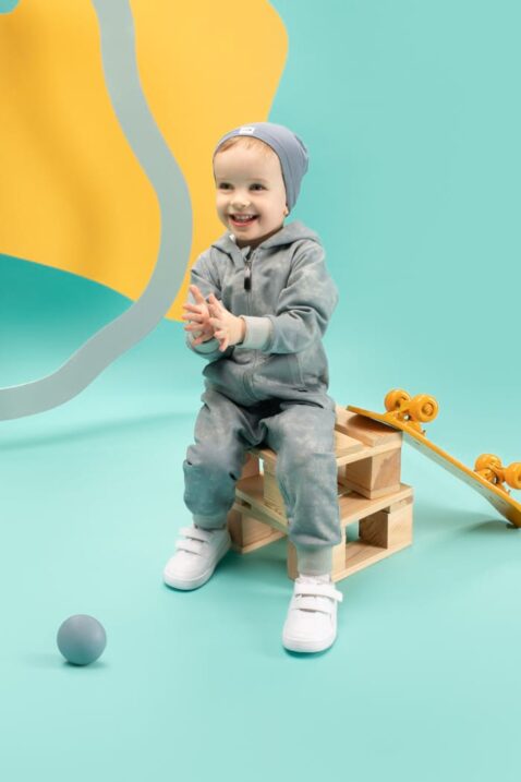 Baby & Kinder Jungen Batik Strampleranzug Einteiler mit Füßen, Kapuze, geteilte Kängerutaschen & Reißverschluss in Mint Blaugrün von Pinokio - Kinderfoto sitzender lachender Junge