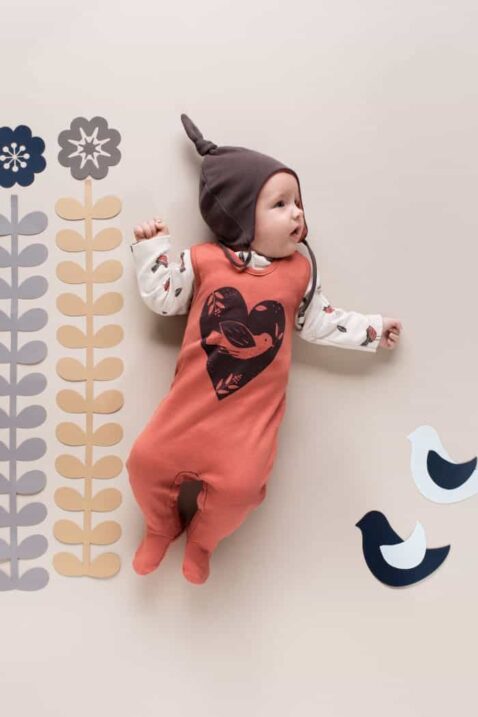 Ziegelroter Baby Strampler mit Fuß, Herz, Vogel Tiermotiv & Druckknöpfen - Mütze mit Ohrenklappen braun von Pinokio - Babyfoto Mädchen liegend mit Einteiler