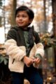 Junge trägt grün beige Baby & Kinder Outdoor Kapuzenjacke Cardigan mit Borg Fellimitat gefüttert für Winter & Herbst von Koko Noko - Kinderfoto stehender Junge mit Teddy Kinderjacke