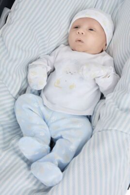 4-teiliges Neugeborenen Geschenkset Geschenkbox in Hellblau Weiß von NEWNESS AMOMI - Babyfoto Junge trägt Shirt, Strampelhose mit Fuß, Mütze & Fäustlinge mit Waschbär Motiv