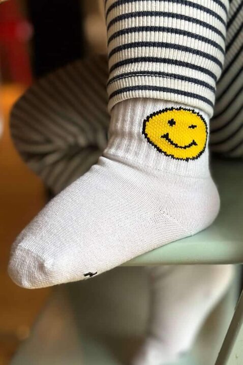 Junge trägt bequeme weisse Premium Tennissocken Baumwollsocken mit gelbem SMILEY Motiv & gerippten Schaft für Babys & Kinder von J.CLAY Socks - Nahaufnahme des Fußes mit hochwertigen Jungensocken & Mädchensocken unifarben