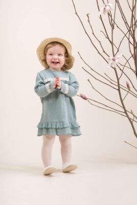 Stehendes, lachendes Mädchen trägt Langarmkleid aus Musselin in Mintgrün & Sommerhut von PINOKIO – Mädchenfoto Baby & Kleinkind Sommeroutfit aus weicher Baumwolle