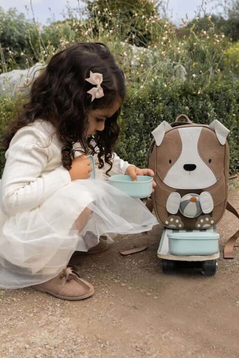 Baby & Kinder Rucksack Dog mit Ohren aus veganem, recyceltem Leder in Vintage Braun für Kita, Kindergarten, Schule von LITTLE WHO - Mädchenfoto kniendes braunhaariges Mädchen mit festlichem weißem Kleid spielt mit Kinderrucksack Hund Henri