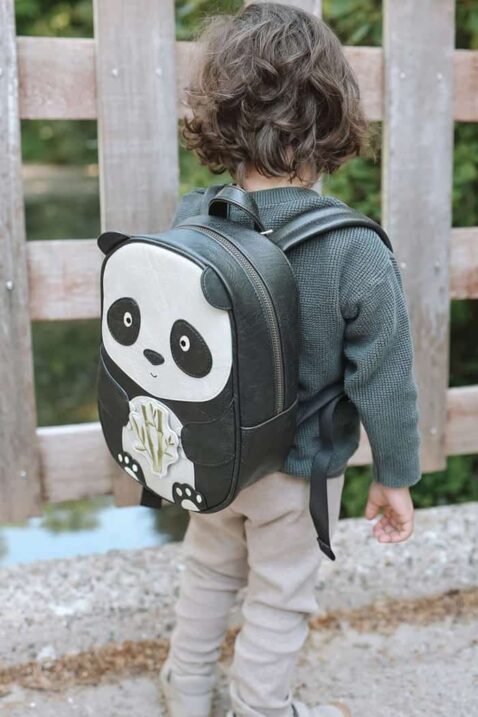 Baby & Kinder Kunstleder Rucksack Panda aus veganem, recyceltem Material in Schwarz für Kita, Kindergarten, Schule, Sport von LITTLE WHO - Kinderfoto Junge steht vor einem Zaun & trägt Kinderrucksack Panda Suki
